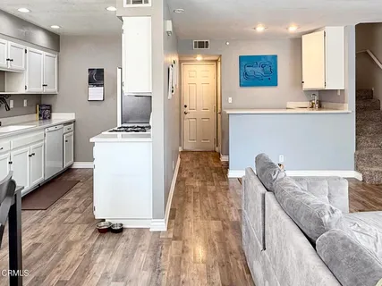 a living room with stainless steel appliances kitchen island granite countertop wooden floor a stove a kitchen island and cabinetry