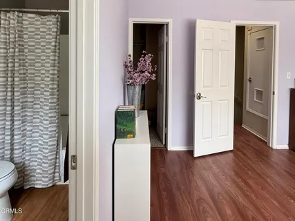 a view of a hallway with wooden floor and a bathroom