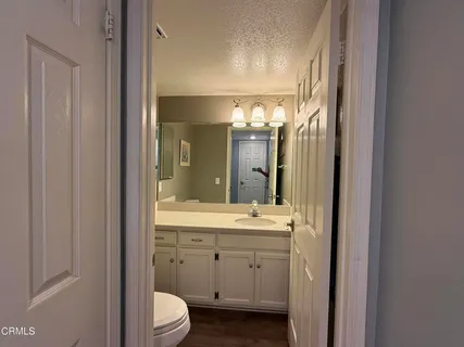a bathroom with a double vanity sink and mirror with toilet