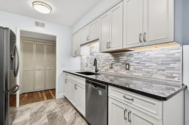 a kitchen with granite countertop a sink stove and refrigerator