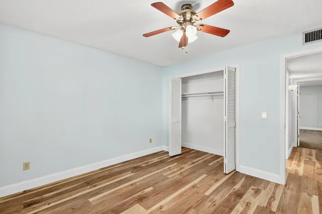 an empty room with closet and a chandelier fan
