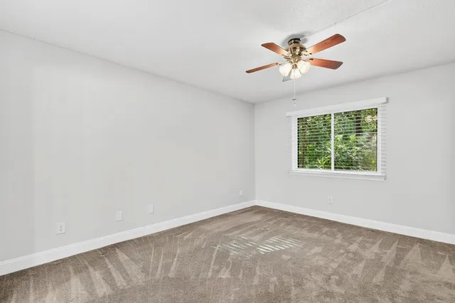 a view of empty room with wooden floor and ceiling fan