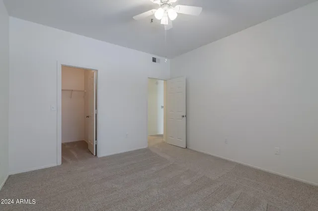 an empty room with windows and fan