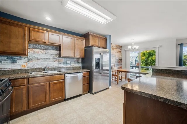 a kitchen with stainless steel appliances granite countertop a sink stove refrigerator and cabinets