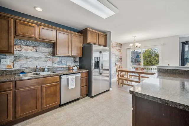 a kitchen with stainless steel appliances granite countertop a refrigerator a sink a stove and cabinets