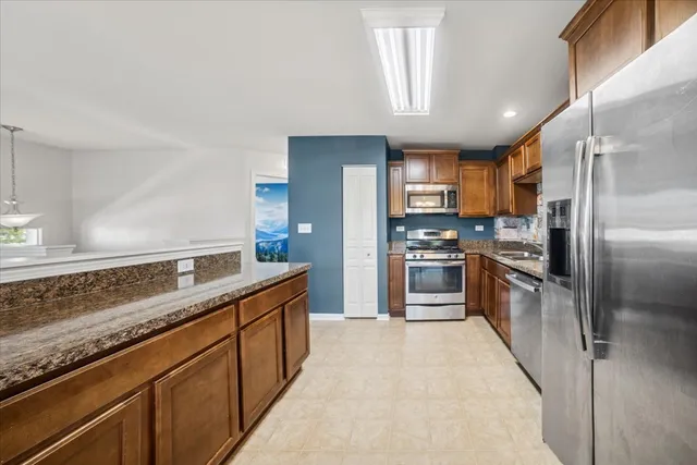 a large kitchen with granite countertop a large counter top stainless steel appliances and cabinets