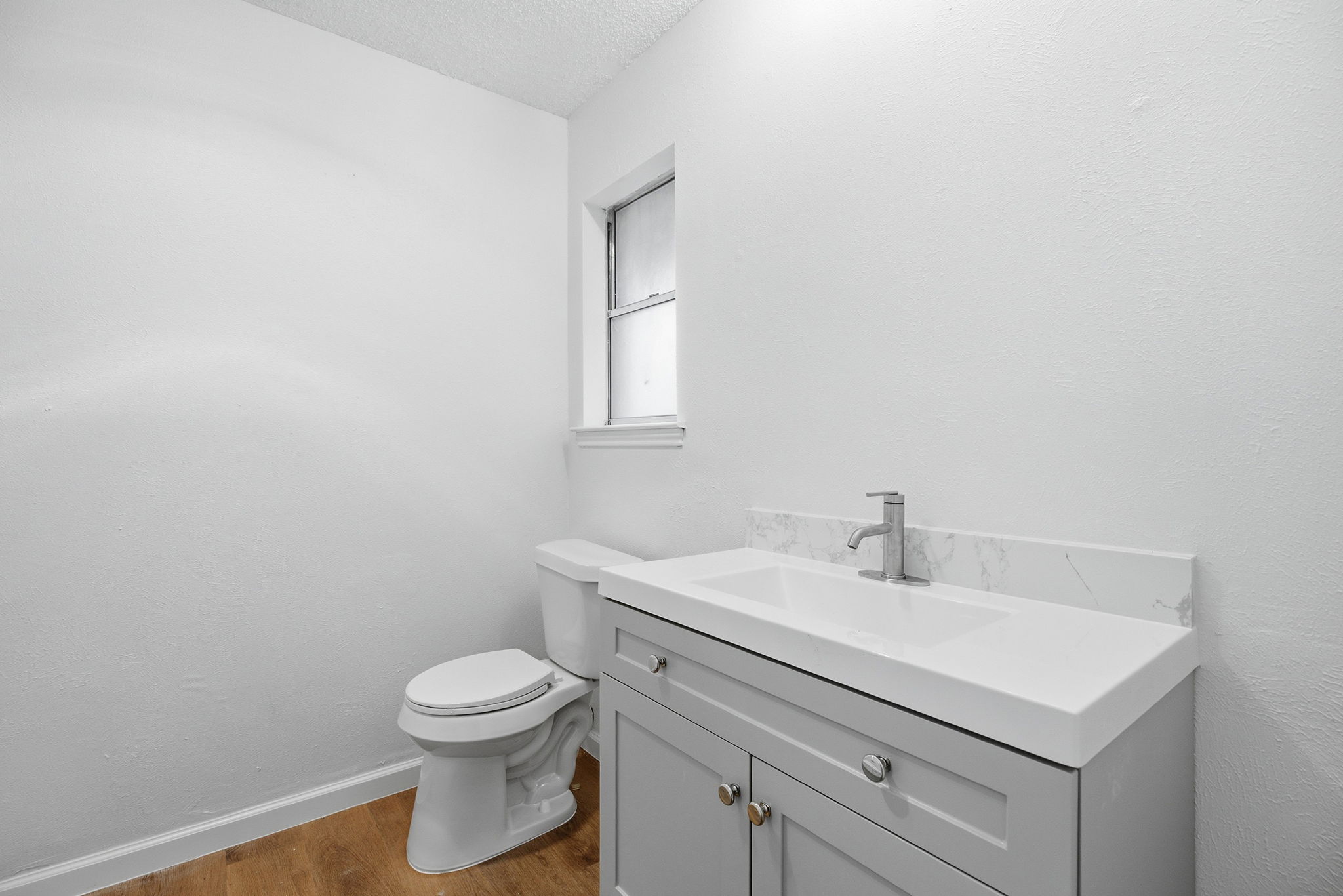7205 Beckett Road Austin, TX 78749 - Photo 27 of 40 A well-appointed lavatory featuring a contemporary vanity and a crisp white toilet, set against durable wooden flooring.