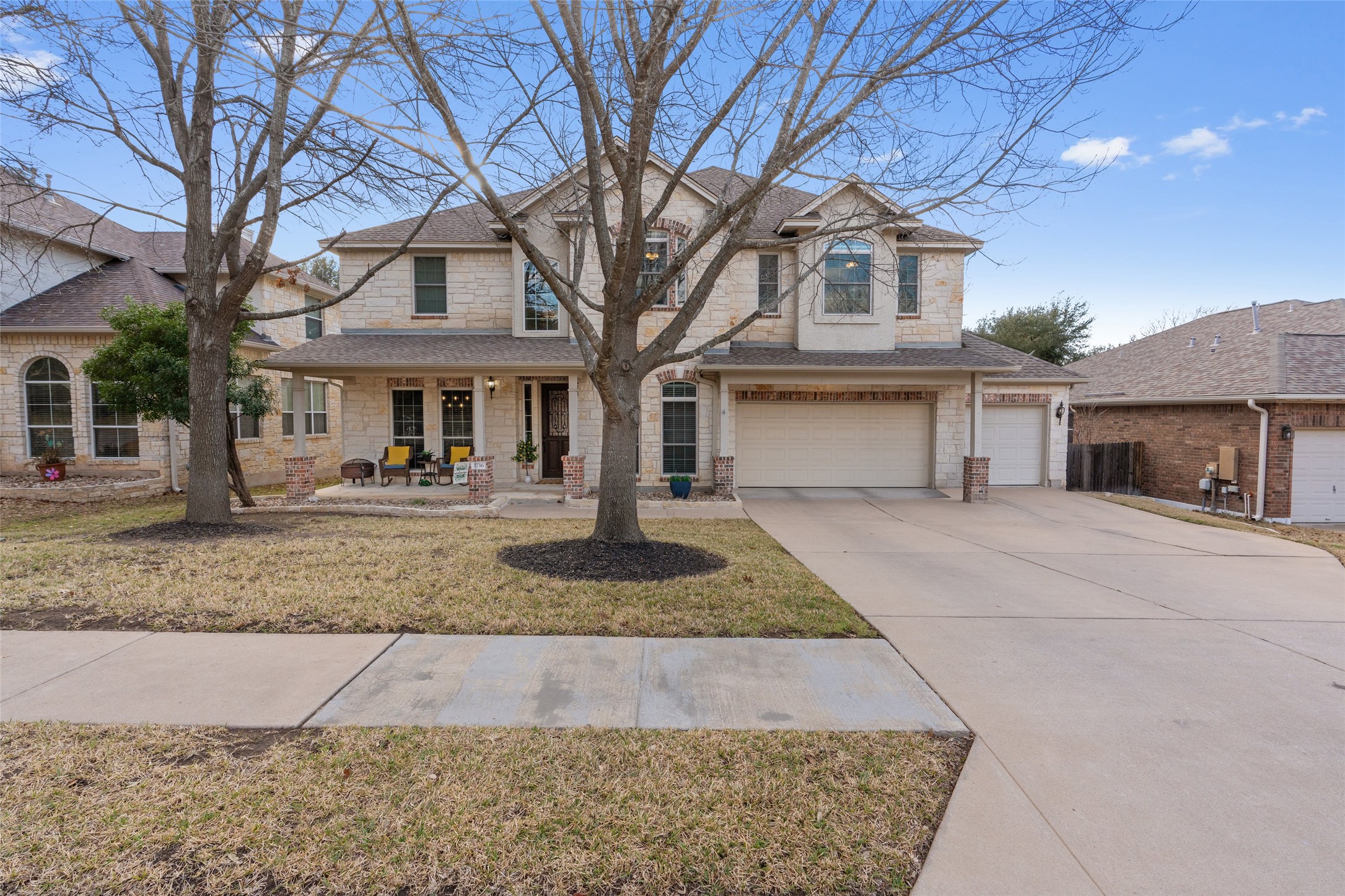 Traditional home with stone siding, a porch, an attached garage, and concrete driveway