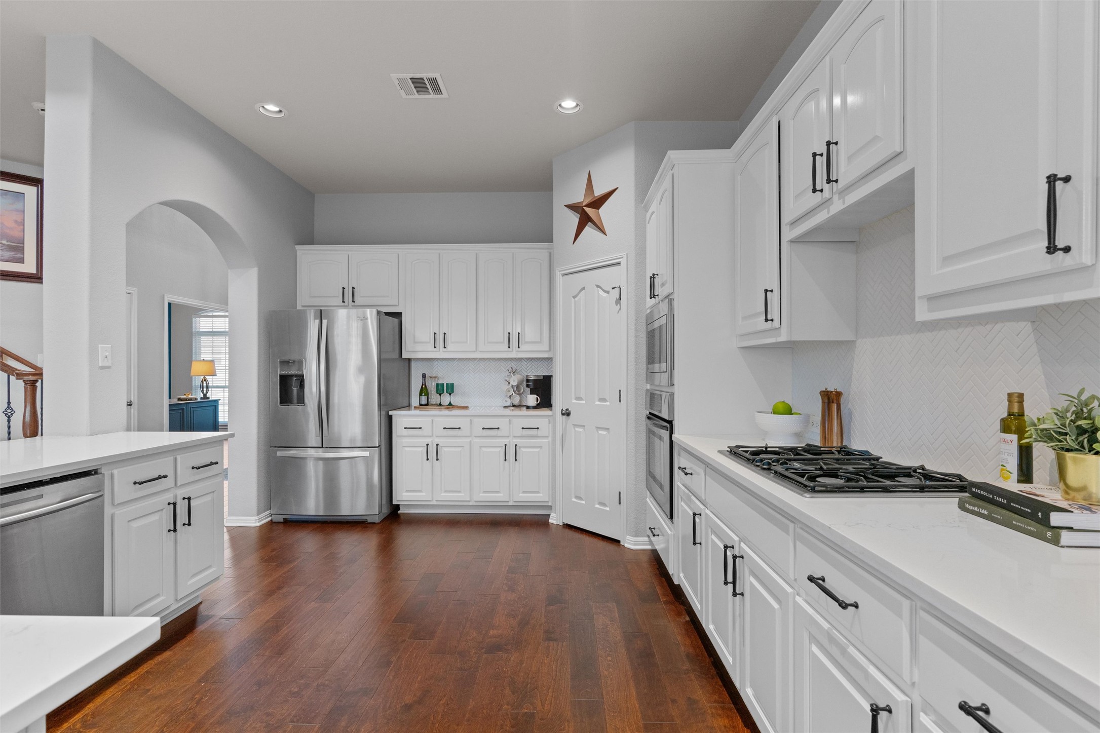 3736 Cerulean Way Round Rock, TX 78681 - Photo 11 of 36 Kitchen with white cabinets, backsplash, stainless steel appliances, dark wood-style flooring, and arched walkways