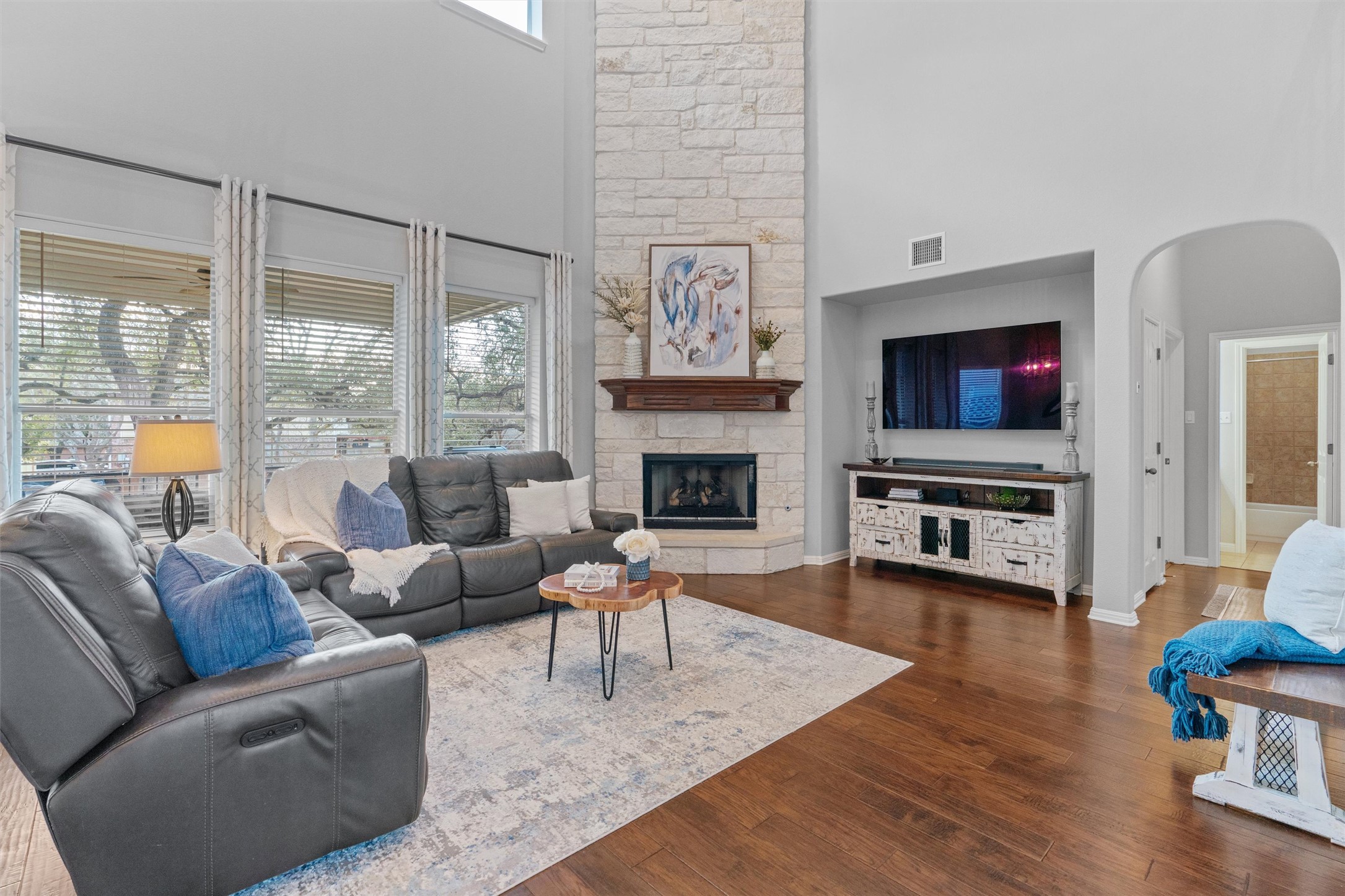 3736 Cerulean Way Round Rock, TX 78681 - Photo 4 of 36 Living area with arched walkways, a high ceiling, dark wood-type flooring, and a stone fireplace