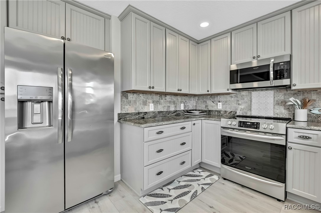 2855 North Rivers Edge Boulevard, Unit 213 Crystal River, FL 34429 - Photo 10 of 62 a kitchen with stainless steel appliances granite countertop a refrigerator stove and white cabinets