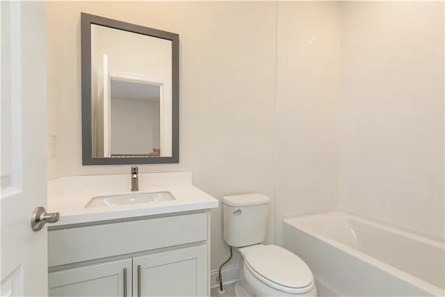 a bathroom with a toilet sink vanity tub and mirror
