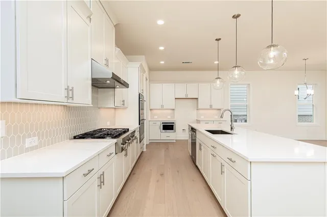 a large white kitchen with stainless steel appliances