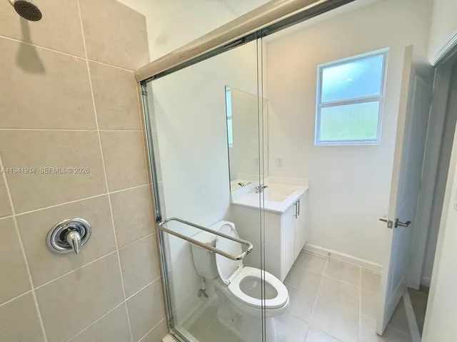 a bathroom with a bathtub shower sink vanity mirror and toilet