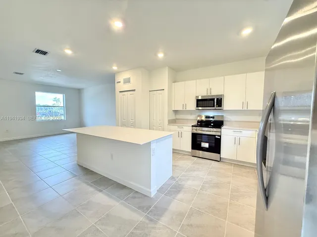 a large kitchen with stainless steel appliances a stove a sink a microwave and a refrigerator