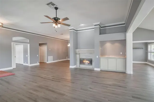 a view of an empty room with wooden floor fireplace and a window