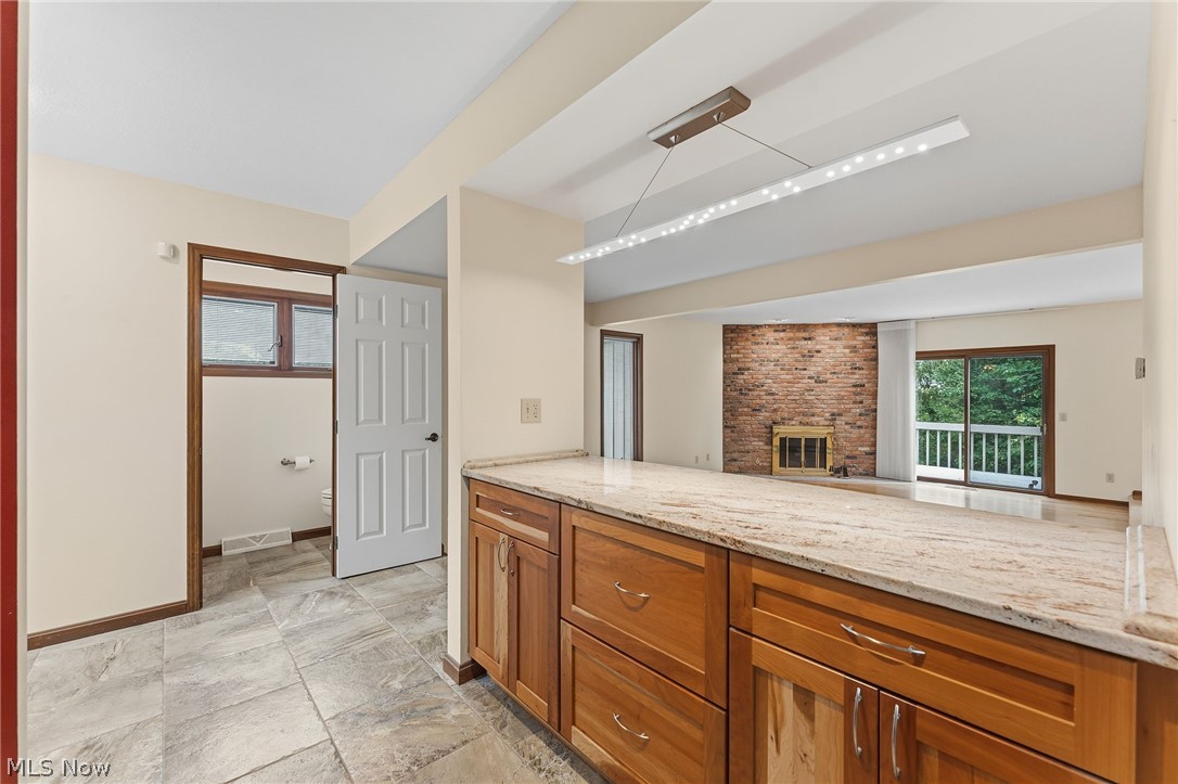 5741 Som Center Road, Unit 1 Solon, OH 44139 - Photo 7 of 50 Kitchen island featuring wood cabinetry, a light-toned stone countertop, and a contemporary linear light fixture