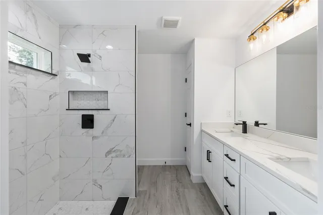 a bathroom with a double vanity sink a toilet and shower