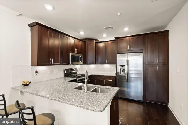 a kitchen with stainless steel appliances granite countertop a sink and a refrigerator