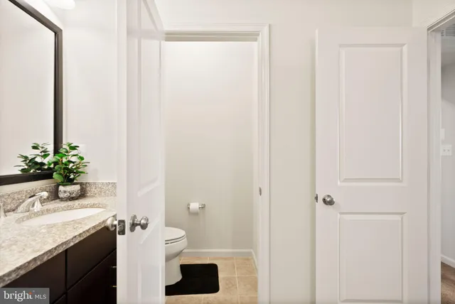 a bathroom with a granite countertop sink a toilet and a mirror
