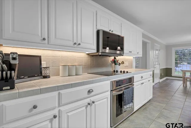 a kitchen with white cabinets and stainless steel appliances