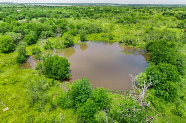 an aerial view of a houses with a yard and lake view