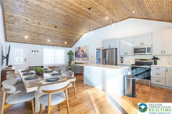 a kitchen with stainless steel appliances kitchen island granite countertop a table chairs and a refrigerator