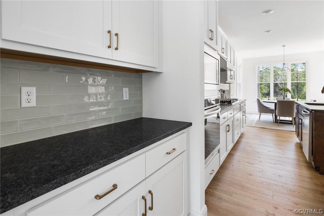 8357 Capernwray Drive Chesterfield, VA 23838 - Photo 27 of 50 a kitchen with granite countertop a stove a sink dishwasher and white cabinets with wooden floor