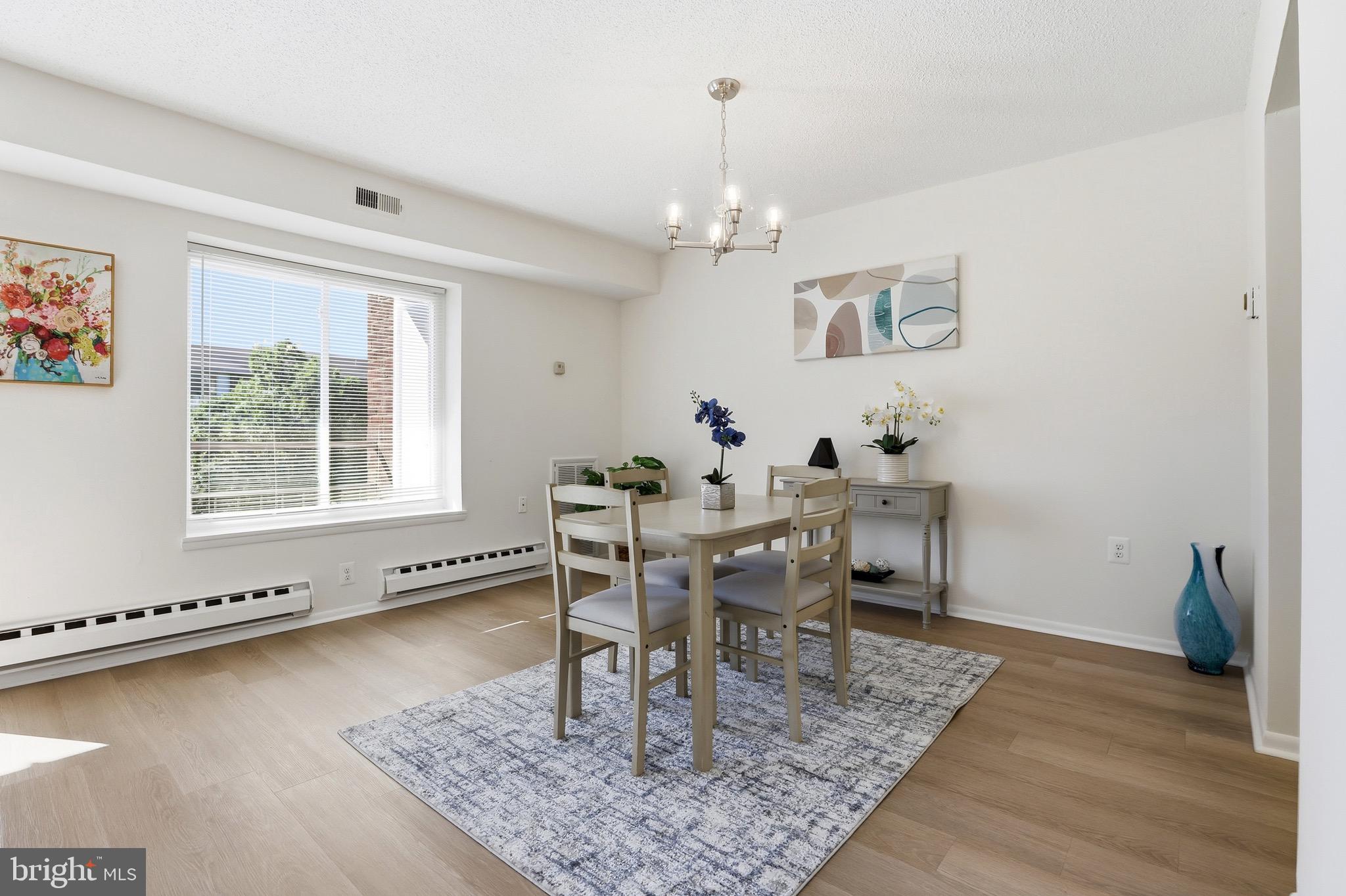3500 Forest Edge Drive, Unit 152F Silver Spring, MD 20906 - Photo 17 of 31 a dining room with wooden floor a chandelier a wooden table and chairs