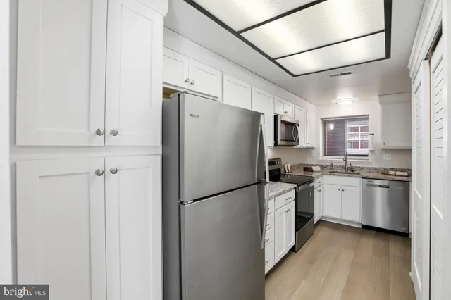 a kitchen with stainless steel appliances granite countertop white cabinets sink and stove