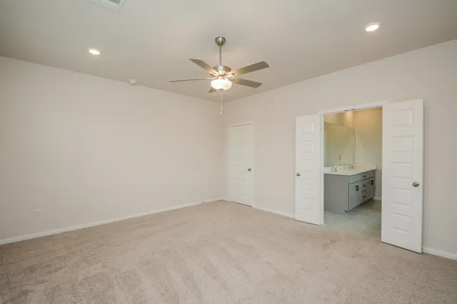 an empty room with closet and a ceiling fan