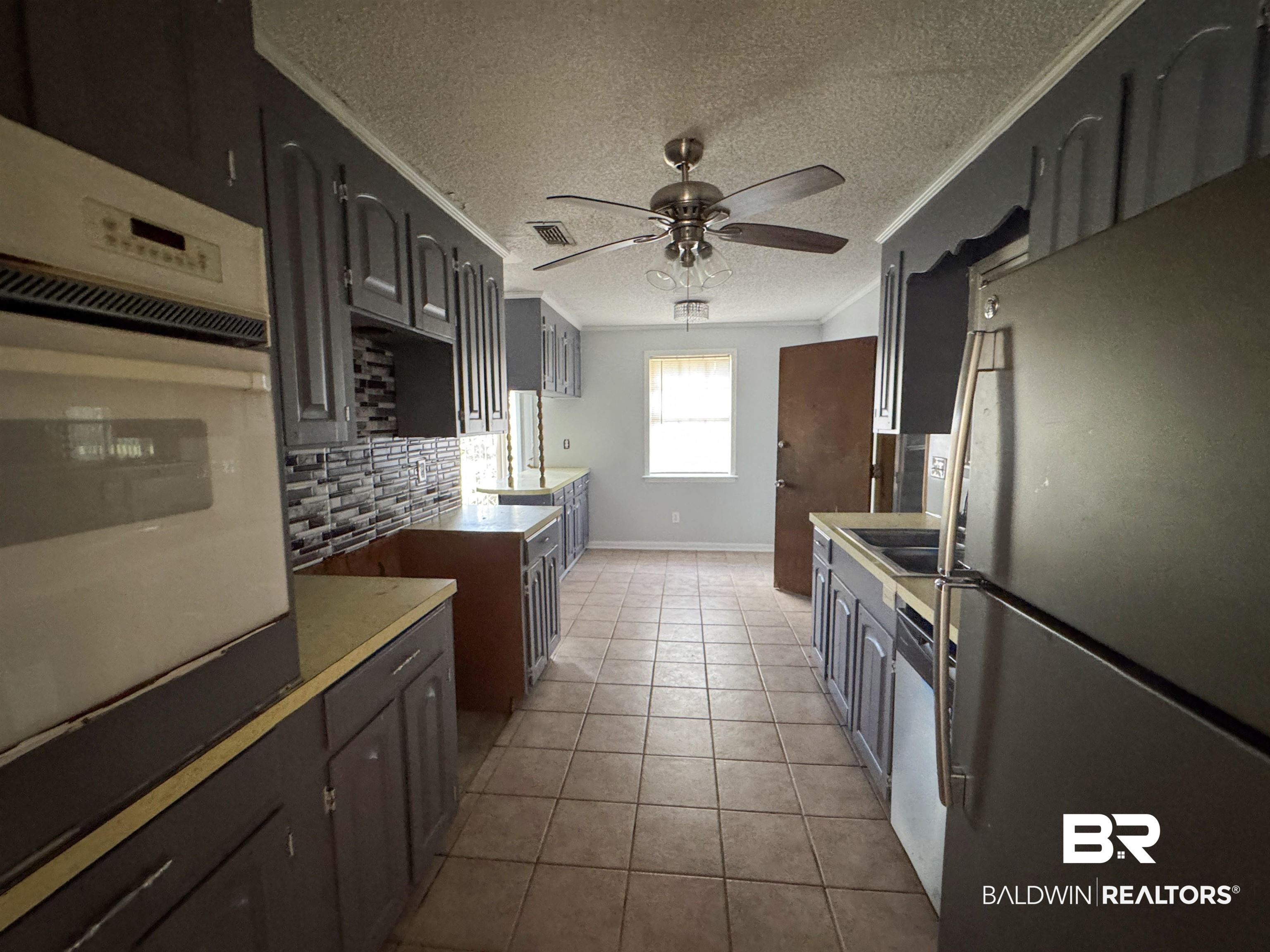 1227 Northgate Drive Atmore, AL 36502 - Photo 4 of 14 Kitchen with stainless steel appliances, ceiling fan, a textured ceiling, light tile patterned floors, and crown molding