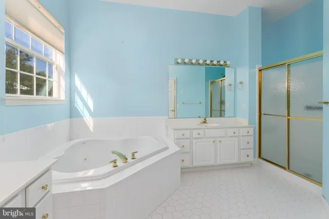 a bathroom with a tub a sink and a large mirror