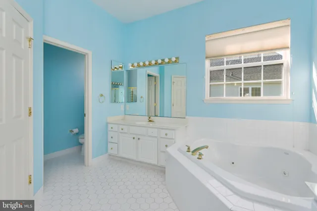 a bathroom with a tub a sink and a large mirror