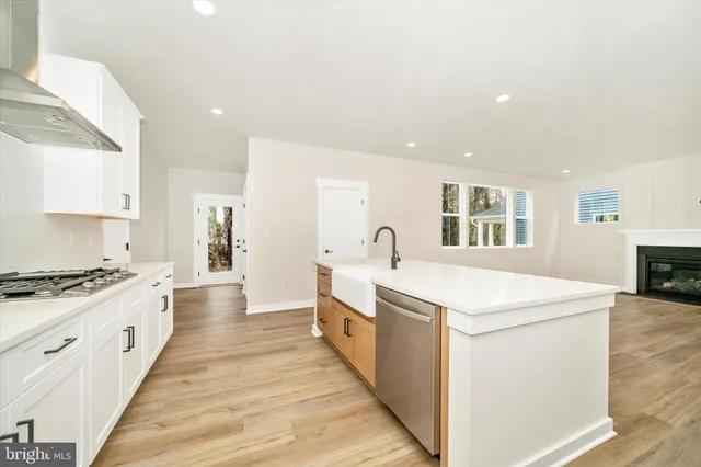 an empty room with wooden floor fireplace and windows