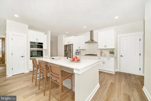 a kitchen with stainless steel appliances a stove top oven a sink dishwasher and a refrigerator with wooden floor