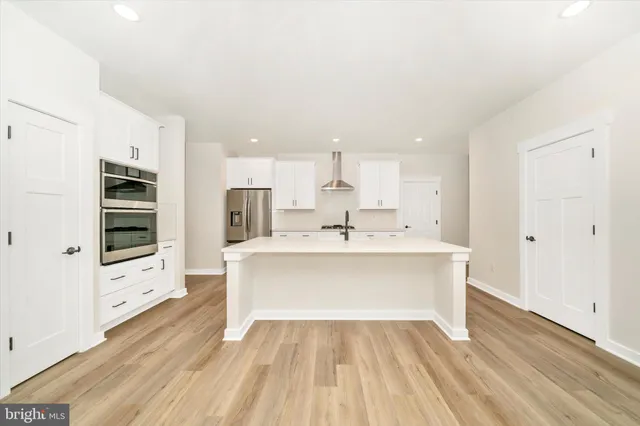 a kitchen with a sink a refrigerator a stove and white cabinets with wooden floor