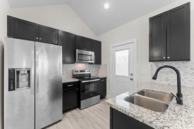 a kitchen with a refrigerator sink and wooden cabinets