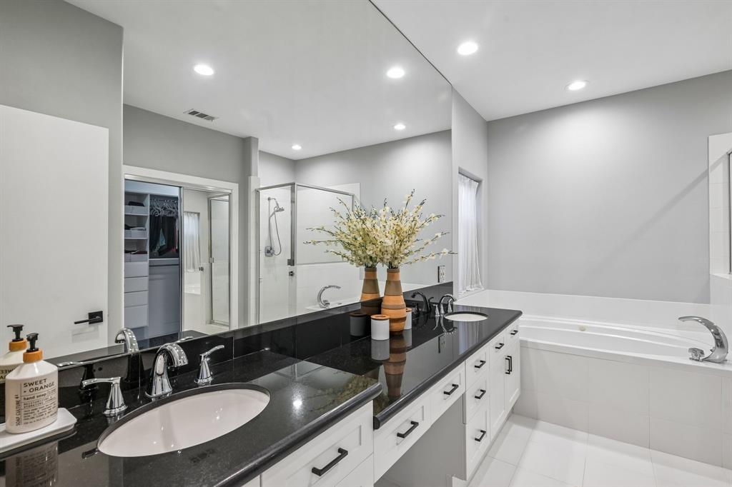 3553 Wheeler Street Dallas, TX 75209 - Photo 28 of 35 Primary en suite with long dual-vanity black granite countertop, soaking tub, and walk-in closet access