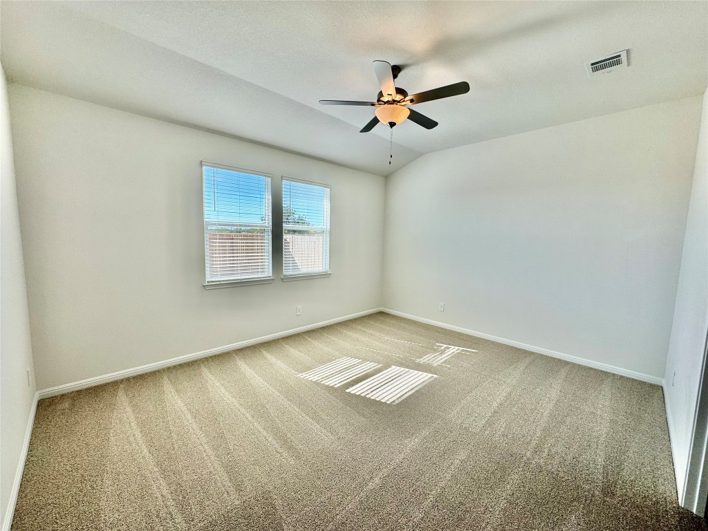 563 Banff Drive Kyle, TX 78640 - Photo 3 of 7 Spare room with light carpet, lofted ceiling, and ceiling fan