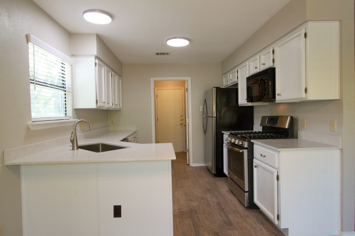 605 Timber Trail Cedar Park, TX 78613 - Photo 12 of 36 a kitchen with stainless steel appliances granite countertop a sink stove a refrigerator a microwave oven with white cabinets and wooden floor