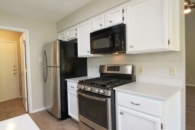 a kitchen with granite countertop a refrigerator stove top oven and sink