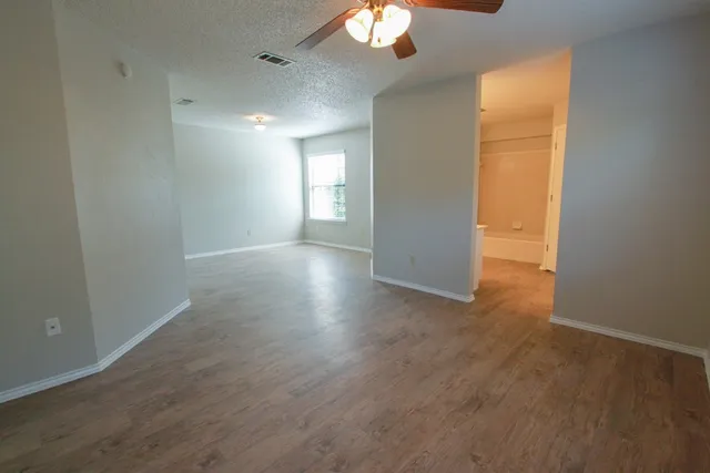 an empty room with wooden floor and windows