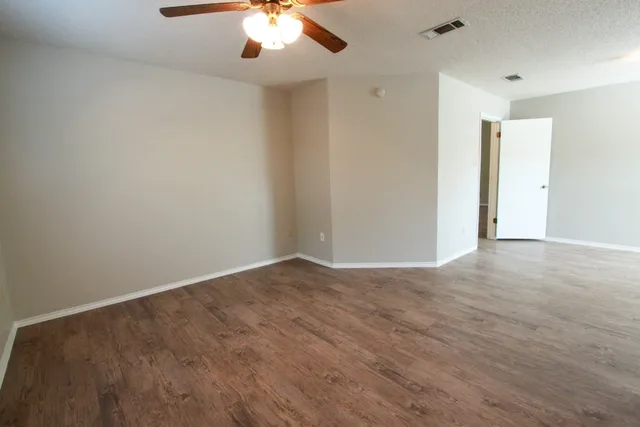 a view of an empty room with a window and wooden floor