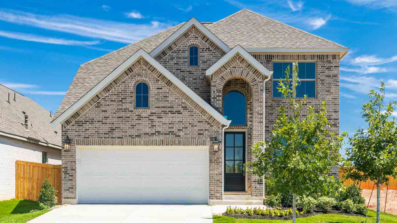 View of front facade with brick siding, concrete driveway, roof with shingles, and a garage
