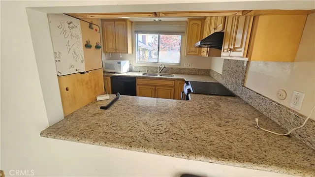 a kitchen with granite countertop a sink a stove a refrigerator and a window