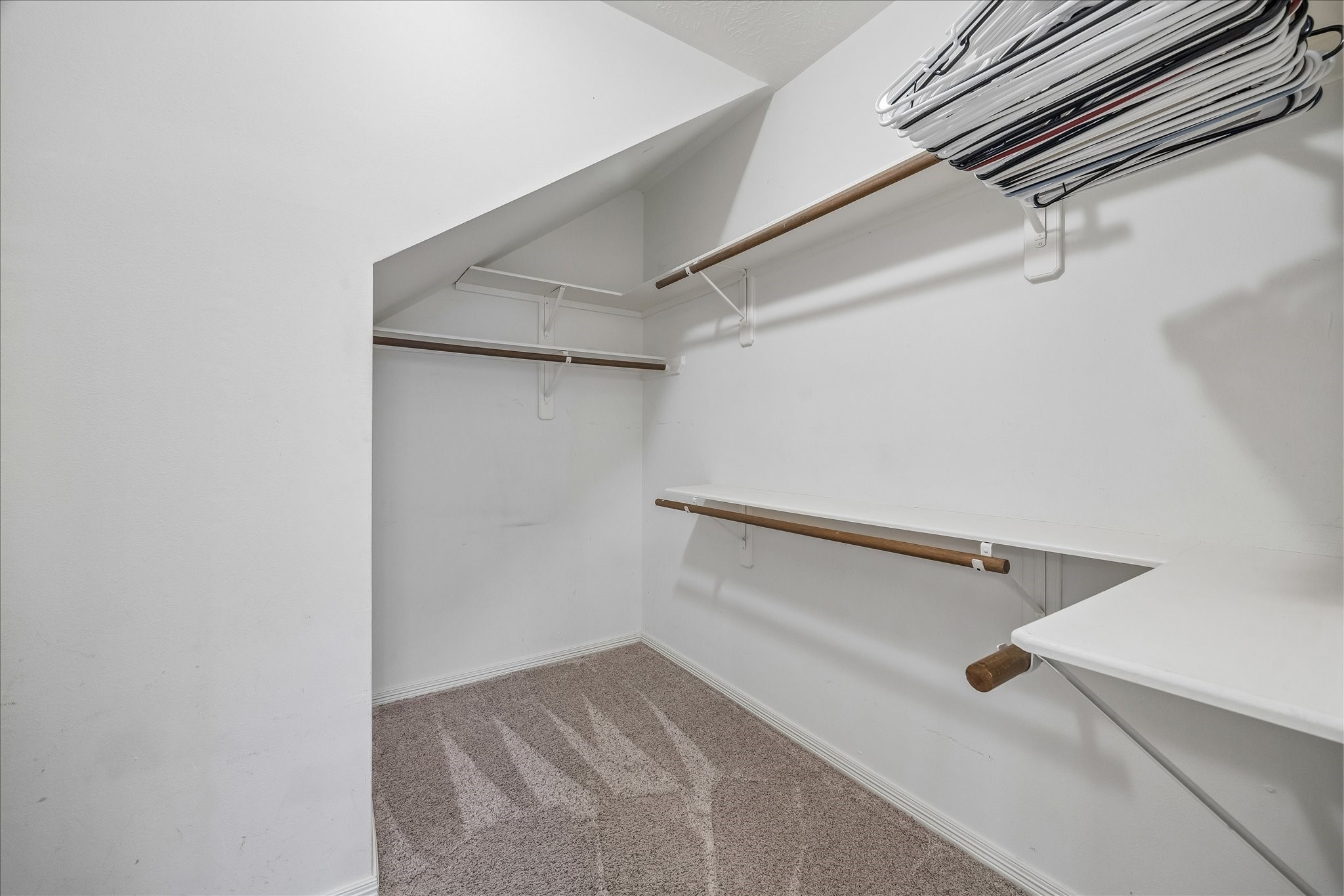 5310 Summerland Ridge Court Houston, TX 77041 - Photo 28 of 46 This is a spacious walk-in closet featuring multiple hanging bars, shelving, and carpeted flooring, ideal for organized storage and accessibility.