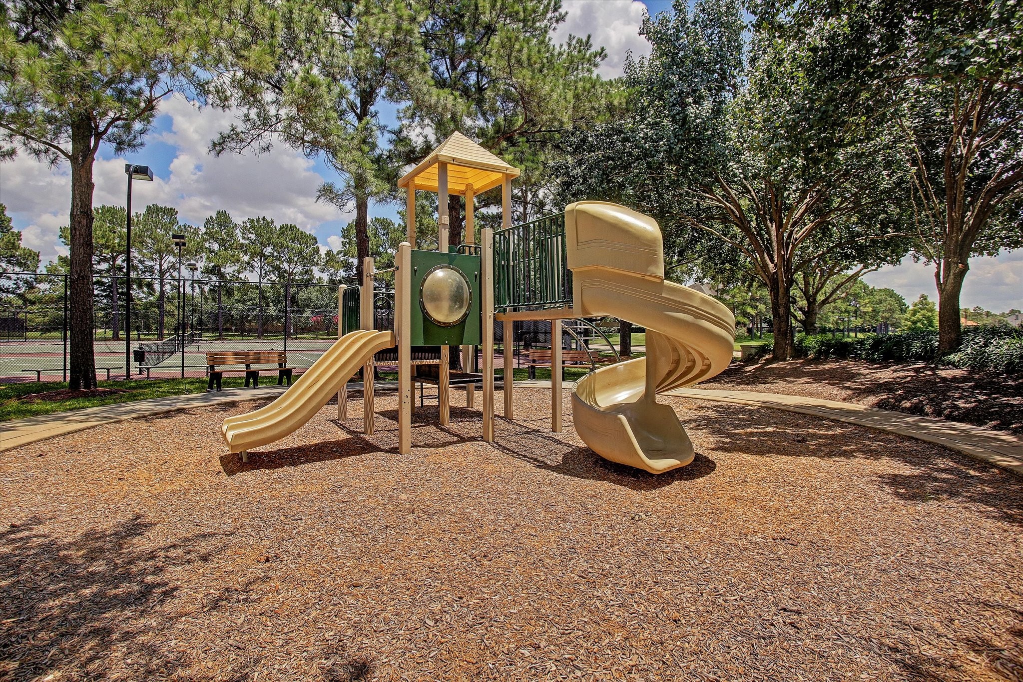 5310 Summerland Ridge Court Houston, TX 77041 - Photo 44 of 46 The neighborhood has plenty of playgrounds with slides and climbing structures, surrounded by trees and next to a tennis court, ideal for families and outdoor activities.