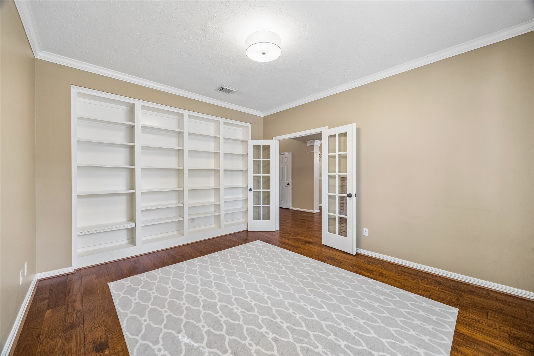 5310 Summerland Ridge Court Houston, TX 77041 - Photo 8 of 46 Bright room with hardwood floors, built-in white bookshelves, and double glass French doors. Neutral walls and ceiling light add a cozy feel, perfect for a home office or library.