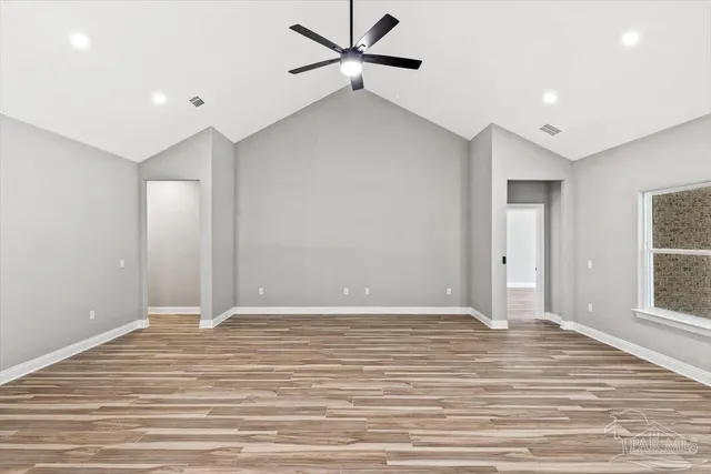 a view of an empty room with window and wooden floor